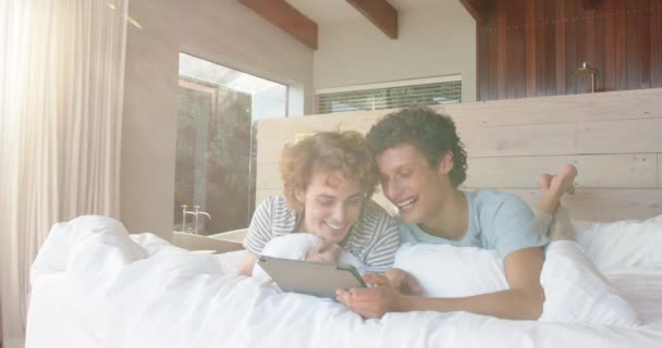 Ευτυχισμένο Ζευγάρι Ομοφυλόφιλων Που Κείτονται Στο Κρεβάτι Και Χρησιμοποιούν Tablet — Αρχείο Βίντεο