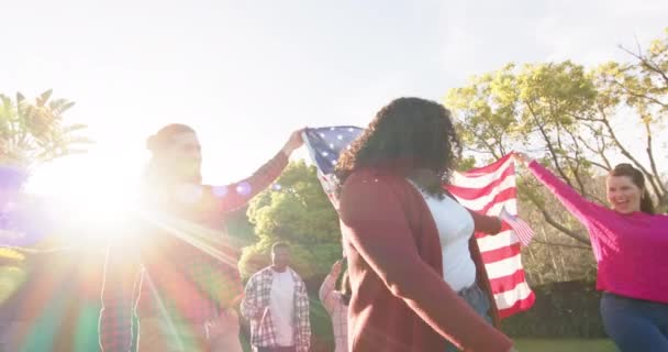 快乐的男女朋友在阳光灿烂的花园里与国旗共舞 爱国主义 美国文化和传统不变 — 图库视频影像