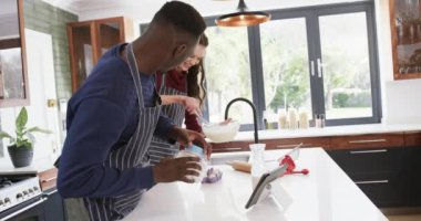 Mutfakta duran, tablet kullanan ve hamur hazırlayan mutlu çift, yavaş çekim. Yemek, yemek pişirme, iletişim, ilişki, birliktelik ve aile hayatı, değişmeden.