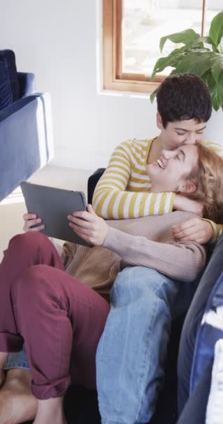 Feliz Casal Lésbico Caucasiano Deitado Sofá Abraçando Usando Tablet Sala — Vídeo de Stock
