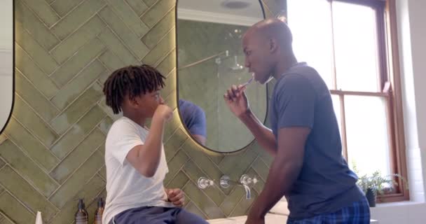 非裔美国人的父亲和儿子在家里的浴室里刷牙 动作缓慢 父亲身份 自我照顾 卫生和家庭生活 — 图库视频影像