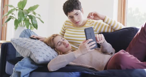 Feliz Casal Lésbico Caucasiano Deitado Sofá Usando Smartphones Rindo Casa — Vídeo de Stock