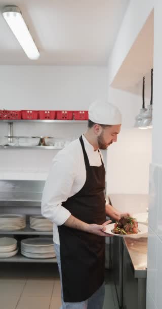 キッチン スローモーション 垂直の皿に調理された料理を保持する白人男性シェフ 食べ物 レストラン ケータリング 変更なし — ストック動画