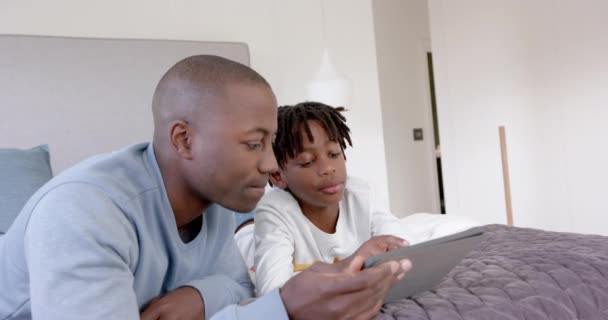 Africký Americký Otec Syn Leželi Doma Posteli Používali Tablet Zpomaleně — Stock video