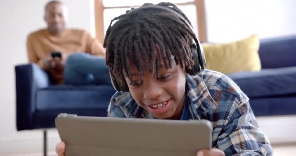 Счастливый Африканский Американец Наушниках Планшетом Лежащим Дома Полу Замедленная Съемка — стоковое видео