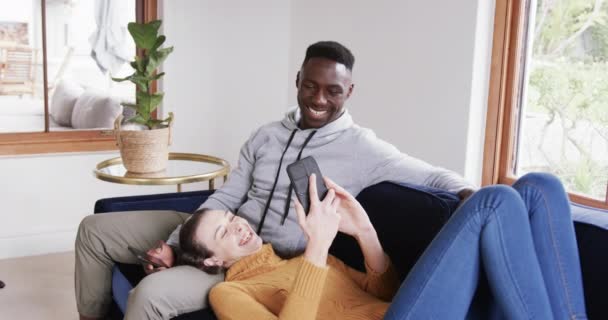 Heureux Couple Diversifié Assis Couché Sur Canapé Utilisant Des Smartphones — Video
