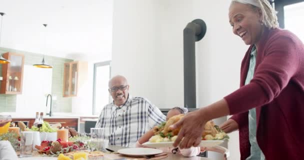 感謝祭の夕食 ゆっくりとした動きで食事を提供するハッピーなアフリカ系アメリカ人の世代の家族 感謝祭 お祝い トータルネス — ストック動画