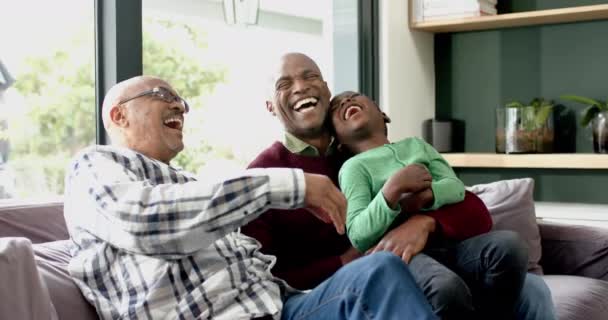 ハッピーアフリカ系アメリカ人の父親 祖父が一緒にソファーに座って笑い ゆっくりとした動きをしました 子供時代 トータルネス 家庭生活 ライフスタイル 変わらない — ストック動画