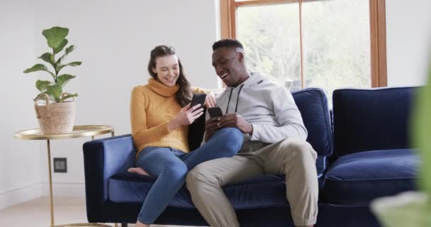 Szczęśliwa Zróżnicowana Para Siedząca Sofie Korzystająca Smartfona Karty Kredytowej Domu — Wideo stockowe