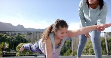 Güneşli bir günde terasta yoga, yavaş çekim ve fotokopi çekerek mutlu anne-kız çiftler. Aile, annelik, fitness, yoga, refah, çocukluk ve birliktelik, değişmemiş.