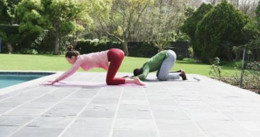 Güneşli bahçede yoga yapan mutlu çift, yavaş çekim, fotokopi uzayı. İlişki, birliktelik, fitness, yoga, refah, değişmemiş.