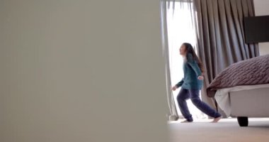 Mutlu çift ırklı anne ve kız güneşli yatak odasında dans ediyor. Aile, annelik, refah, çocukluk ve beraberlik, değişmemiş..