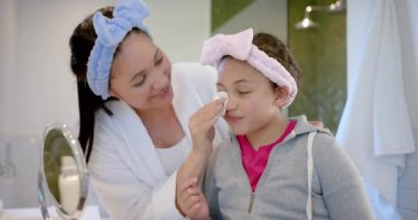 Saçında bantla güneşli banyoda yüzleriyle ilgilenen mutlu anne ve kız. Kişisel bakım, hijyen, aile, annelik, çocukluk, birliktelik ve aile hayatı, değişmemiş..