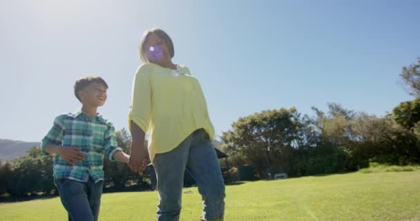 ハッピーなおばあちゃんと孫が日当たりの良い庭を歩き ゆっくりとした動きをしています トータル ライフスタイル 変わらない — ストック動画