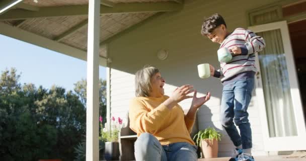 快乐的长辈奶奶和孙子抱着杯子站在阳台上 慢动作 夏天和生活方式 — 图库视频影像
