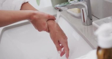 Çift ırklı kadınların tuvalette ellerini yıkaması, ağır çekimde. Kişisel bakım, hijyen, yaşam tarzı ve ev hayatı.