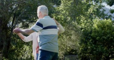 Güneşli bahçede dans eden son sınıf beyaz çift, yavaş çekim. Kıdemli yaşam tarzı, birliktelik, yaz ve doğa, değişmez..