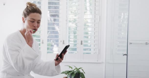 Mulher Biracial Feliz Escovando Dentes Usando Smartphone Banheiro Câmera Lenta — Vídeo de Stock