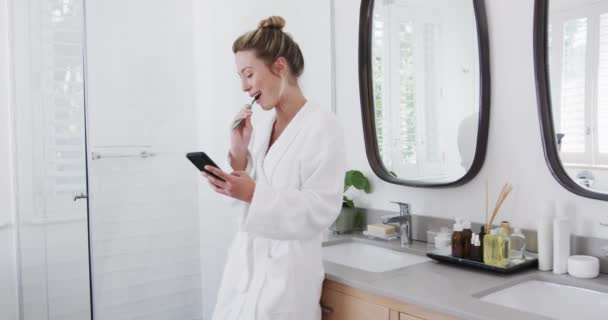 Mulher Biracial Escovando Dentes Usando Smartphone Banheiro Câmera Lenta Autocuidado — Vídeo de Stock