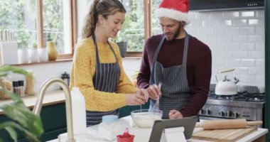 Mutlu ve çeşitli çiftler evde mutfakta Noel kurabiyeleri pişiriyor, ağır çekimde. İlişki, birliktelik, iletişim, yemek, tarif, noel, yaşam tarzı ve aile hayatı, değiştirilmemiş.