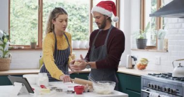 Mutlu ve çeşitli çiftler evde mutfakta Noel kurabiyeleri pişiriyor, ağır çekimde. İlişki, birliktelik, iletişim, yemek, tarif, noel, yaşam tarzı ve aile hayatı, değiştirilmemiş.