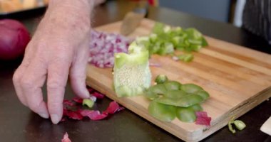 Evde, mutfakta sebze kabuğu temizleyen kıdemli beyaz adamın orta kesimi, ağır çekim. Kıdemli yaşam tarzı, yemek, yemek, sağlıklı yaşam ve ev hayatı..