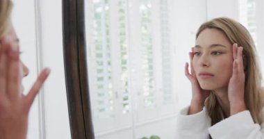 Çift ırklı bir kadın banyoda aynaya bakıyor, ağır çekimde. Kişisel bakım, yaşam tarzı ve ev hayatı, değişmedi..