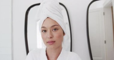 Banyoda kafasında havlu olan mutlu çift ırklı kadın portresi, yavaş çekim, fotokopi alanı. Kişisel bakım, yaşam tarzı ve ev hayatı, değişmedi..