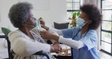 Afrikalı Amerikalı kadın doktor tekerlekli sandalyedeki yaşlı kadın hastaya oksijen veriyor, ağır çekimde. Sağlık hizmetleri, sağlık hizmetleri, hijyen, koronavirüs ve yaşlı yaşam tarzı, değişmemiş..