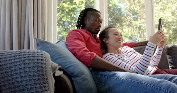Heureux Couple Diversifié Détendre Sur Canapé Utilisant Tablette Dans Salon — Video