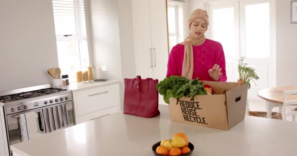 Mujer Biracial Hijab Con Compras Comestibles Cocina Casa Con Espacio — Vídeos de Stock