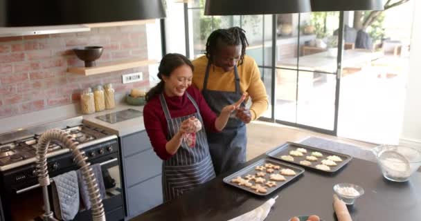 Szczęśliwa Zróżnicowana Para Fartuchach Piecze Świąteczne Ciasteczka Tańczy Kuchni Zwolnione — Wideo stockowe
