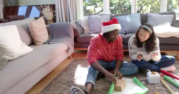 Щаслива Різноманітна Пара Сидить Підлозі Вдома Обгортаючи Різдвяні Подарунки Копіюючи — стокове відео
