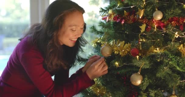 クリスマスツリーと笑顔 ゆっくりとした動きを飾るハッピーな女性 クリスマス お祝い 家庭生活とライフスタイル 変わらない — ストック動画
