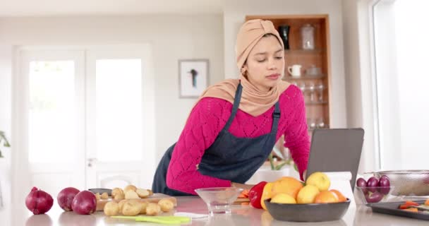 Mulher Biracial Hijab Usando Tablet Preparando Comida Cozinha Casa Com — Vídeo de Stock