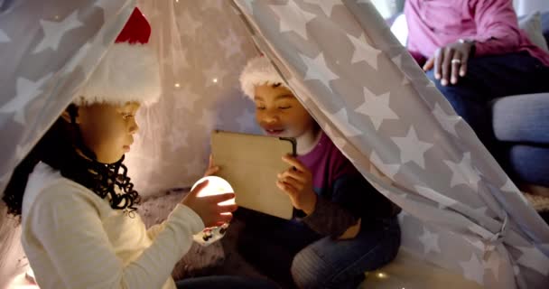 快乐的非洲裔美国兄弟姐妹 戴着圣诞礼帽 毛毯帐篷里挂着石碑 动作缓慢 圣诞节 家庭和团聚 — 图库视频影像