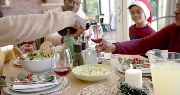 ハッピーアフリカ系アメリカ人の父親は 家族のクリスマスディナーテーブルで祖父母のためにワインを注いでいます クリスマス お祝い トータルネスと家庭生活 変わらない — ストック動画