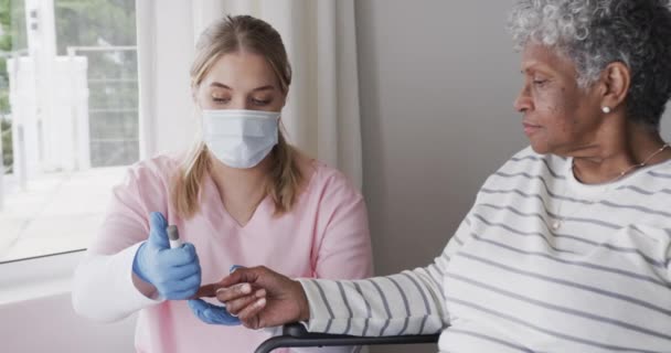 Blanke Vrouwelijke Verpleegster Met Gezichtsmasker Die Suiker Controleert Van Senior — Stockvideo