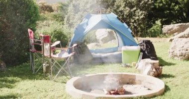 Sigara içme, çadır, sandalyeler ve kırsal kesimde kamp malzemeleri fotokopi alanı, ağır çekim. Kamp, boş zaman, seyahat ve açık hava yaşam tarzı, değişmemiş..