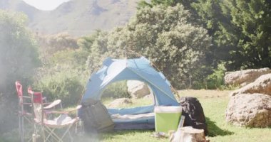 Sigara içme, çadır, sandalyeler ve kırsal kesimde kamp malzemeleri fotokopi alanı, ağır çekim. Kamp, boş zaman, seyahat ve açık hava yaşam tarzı, değişmemiş..