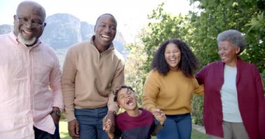 Mutlu Afro-Amerikan ebeveynler ve büyük ebeveynler güneşli bahçede birlikte yürüyorlar. Yaz, aile, boş zaman, yaşam tarzı ve birliktelik, değişmemiş..