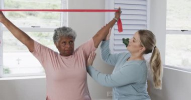 Kafkas hemşire ve yaşlı kadın lastik bantla egzersiz yapıyorlar, kopyalama alanı, yavaş çekim. Yaşlılar yaşam tarzı, hemşire, sağlık hizmetleri, bakım, tıp, meslek, iş kavramı, değiştirilmemiş.