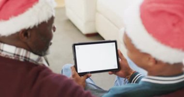 Mutlu Afro-Amerikan baba ve yetişkin oğul noel şapkaları içinde tablet, kopyalama alanı ve ağır çekim kullanarak. İletişim, babalık, aile, Noel, gelenek, kutlama ve yaşam tarzı, değiştirilmemiş.