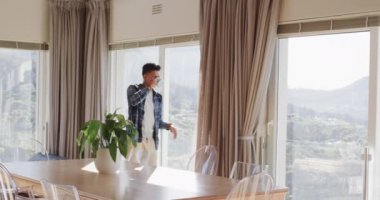 Afro-amerikan bir adam penceresinde kahve içiyor, güneşli dağ manzaralı, kopyalama alanı, yavaş çekim. Düşünce, rahatlama, refah, doğa, ev hayatı ve yaşam tarzı, değişmemiş..