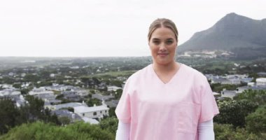 Gülümseyen beyaz hemşirenin portresi manzara karşısında fotokopi alanı ile, yavaş çekim. Hemşire, sağlık hizmetleri, ilaç, meslek, iş kavramı, değiştirilmemiş.