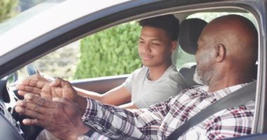 Mutlu Afro-Amerikan babası sürüş dersinden önce gülümseyen oğlunu arabada eğitiyor. Sürücülük, öğretim, öğrenme, birliktelik, babalık, aile ve yaşam tarzı, değişmemiş.