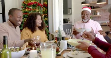 Mutlu Afro-Amerikan çoklu kuşak ailesi Noel yemeği masasında tabak dağıtıyor. Noel, kutlama, aile, gelenek, birliktelik ve aile hayatı değişmedi..