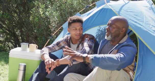 快乐的非洲裔美国人父亲和儿子坐在帐篷外 在阳光下聊天 动作缓慢 闲暇时间 父亲身份 家庭和户外生活方式 — 图库视频影像