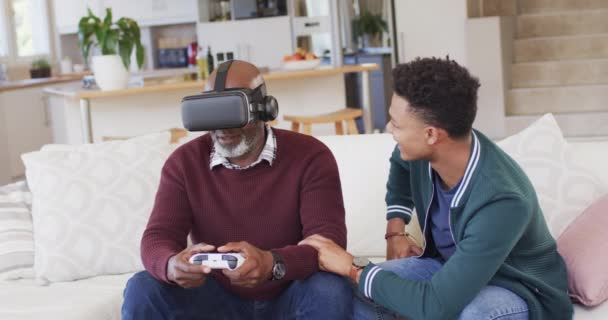 快乐的非洲裔美国父亲使用Vr耳机和游戏垫与成年儿子在家里 慢动作 电子游戏 业余时间 父亲身份 家庭和家庭生活 — 图库视频影像