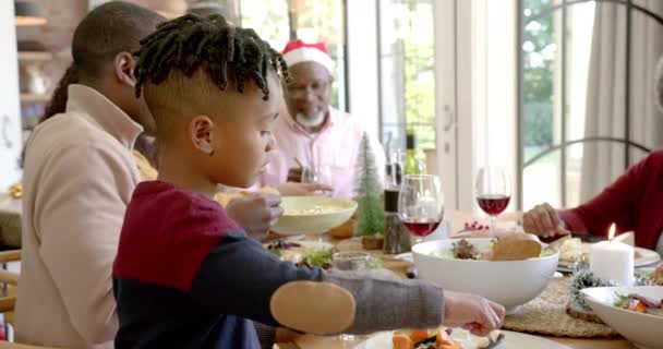 ハッピーアフリカ系アメリカ人の息子は 多世代の家族のクリスマスディナーテーブルで笑っている クリスマス お祝い トータルネスと家庭生活 変わらない — ストック動画